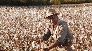 Movie still from “Honeydripper” (2007), directed by John Sayles – A man in a field of cotton with a hat on; Medium shot, Over the shoulder angle