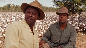 Movie still from “Honeydripper” (2007), directed by John Sayles – A couple of men sitting next to each other in a field; Close Up shot, Over the shoulder angle