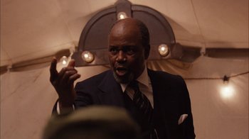 Movie still from “Honeydripper” (2007), directed by John Sayles – A man in a suit and tie talking to a crowd of onlookers; Close Up shot, Low angle