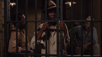Movie still from “Honeydripper” (2007), directed by John Sayles – A man holding a cell phone behind bars; Medium shot, High angle