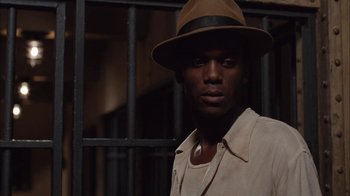 Movie still from “Honeydripper” (2007), directed by John Sayles – A man wearing a hat standing in front of a metal fence; Close Up shot, Low angle