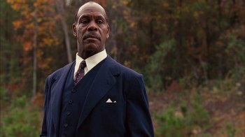 Movie still from “Honeydripper” (2007), directed by John Sayles – A man in a suit and tie standing in front of a forest; Close Up shot, Low angle