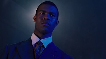 Movie still from “Honeydripper” (2007), directed by John Sayles – A man wearing a suit and tie in a dark room; Close Up shot, Low angle