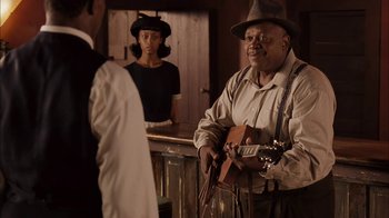 Movie still from “Honeydripper” (2007), directed by John Sayles – A man holding a guitar standing next to a woman; Medium shot, Over the shoulder angle