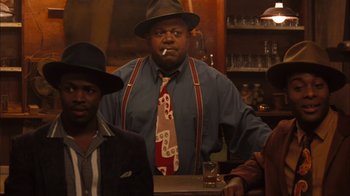 Movie still from “Honeydripper” (2007), directed by John Sayles – A group of men sitting at a table with drinks; Medium shot, Over the shoulder angle