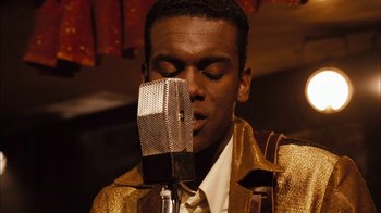 Movie still from “Honeydripper” (2007), directed by John Sayles – A man in a gold jacket is singing into a microphone; Close Up shot, High angle