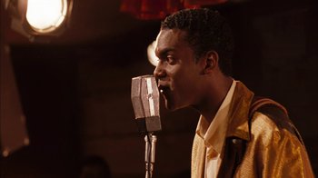 Movie still from “Honeydripper” (2007), directed by John Sayles – A man is singing into a microphone in front of a crowd; Close Up shot, Over the shoulder angle