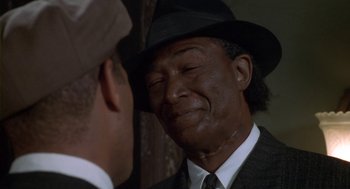 Movie still from “Hoodlum” (1997), directed by Bill Duke – A man wearing a suit and a hat is looking at another man in a suit; Close Up shot, Over the shoulder angle