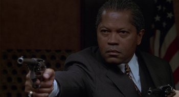 Movie still from “Hoodlum” (1997), directed by Bill Duke – A man in a suit and tie holding a gun in his right hand; Close Up shot, Low angle