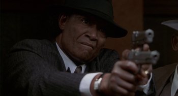 Movie still from “Hoodlum” (1997), directed by Bill Duke – An older man wearing a suit and a hat is holding a gun; Close Up shot, High angle