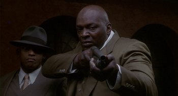 Movie still from “Hoodlum” (1997), directed by Bill Duke – A man in a suit and tie holding a gun; Close Up shot, Low angle