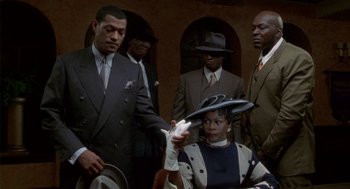 Movie still from “Hoodlum” (1997), directed by Bill Duke – A group of men standing around a woman wearing a hat; Medium shot, Low angle