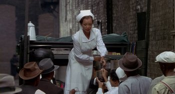 Movie still from “Hoodlum” (1997), directed by Bill Duke – A woman in a nurse's uniform is holding a pan of food; Medium shot, High angle