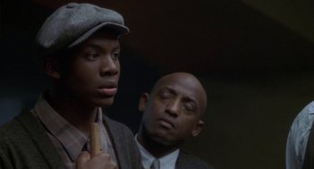 Movie still from “Hoodlum” (1997), directed by Bill Duke – A man and a young boy standing next to each other; Close Up shot, Over the shoulder angle