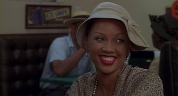 Movie still from “Hoodlum” (1997), directed by Bill Duke – A woman wearing a hat and smiling for the camera; Close Up shot, Over the shoulder angle