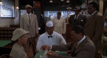Movie still from “Hoodlum” (1997), directed by Bill Duke – A group of people sitting around a table; Medium shot, High angle