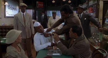 Movie still from “Hoodlum” (1997), directed by Bill Duke – A group of men standing next to each other in front of a table; Medium shot, High angle