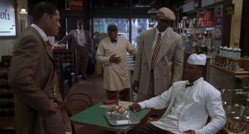 Movie still from “Hoodlum” (1997), directed by Bill Duke – A group of men standing around a table in a restaurant; Medium shot, Over the shoulder angle