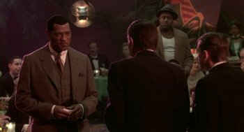 Movie still from “Hoodlum” (1997), directed by Bill Duke – A group of men standing around in a room; Medium shot, Over the shoulder angle