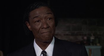 Movie still from “Hoodlum” (1997), directed by Bill Duke – A man in a suit and tie looking at the camera; Close Up shot, Low angle