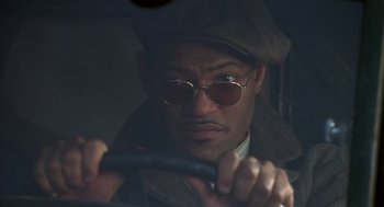 Movie still from “Hoodlum” (1997), directed by Bill Duke – A man wearing a hat and sunglasses driving a car; Close Up shot, Low angle