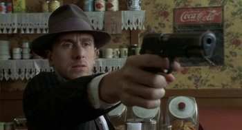 Movie still from “Hoodlum” (1997), directed by Bill Duke – A man holding a gun while wearing a hat; Close Up shot, Over the shoulder angle