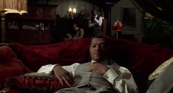 Movie still from “Hoodlum” (1997), directed by Bill Duke – A man laying on a couch in a living room; Medium shot, Low angle