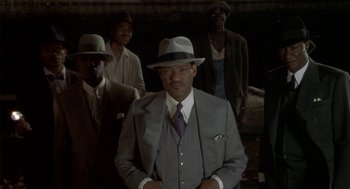 Movie still from “Hoodlum” (1997), directed by Bill Duke – A man in a suit and hat standing in front of a group of men; Medium shot, Low angle