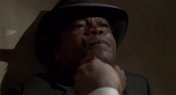 Movie still from “Hoodlum” (1997), directed by Bill Duke – A man in a suit and a hat holding a knife; Close Up shot, High angle