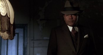 Movie still from “Hoodlum” (1997), directed by Bill Duke – A man in a suit and hat standing in a dark room; Close Up shot, Low angle