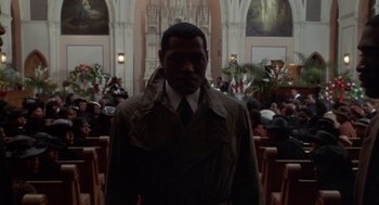 Movie still from “Hoodlum” (1997), directed by Bill Duke – A man wearing a trench coat standing in front of a church; Medium shot, Low angle