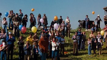 Movie still from “Hooper” (1978), directed by Hal Needham – A group of people standing on top of a grass covered hill; Extreme Wide shot, High angle