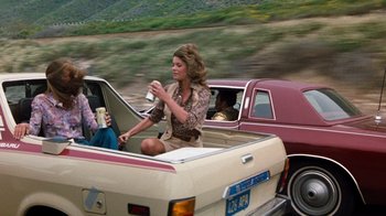 Movie still from “Hooper” (1978), directed by Hal Needham – A woman sitting in the back of a pick - up truck; Wide shot, Over the shoulder angle