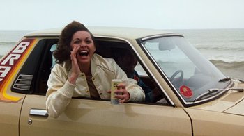Movie still from “Hooper” (1978), directed by Hal Needham – A woman in the driver's seat of a car talking on the phone; Medium shot, Over the shoulder angle