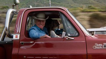 Movie still from “Hooper” (1978), directed by Hal Needham – An older man in a cowboy hat driving a red truck; Medium shot, Over the shoulder angle