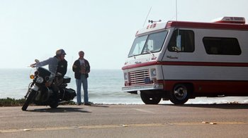 Movie still from “Hooper” (1978), directed by Hal Needham – Two men standing on the side of the road next to a van; Wide shot, Low angle