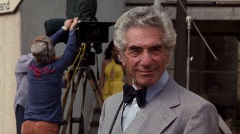 Movie still from “Hooper” (1978), directed by Hal Needham – An older man wearing a suit and bow tie in front of a camera; Close Up shot, Low angle