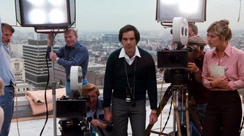 Movie still from “Hooper” (1978), directed by Hal Needham – A man standing in front of a camera on top of a building; Medium shot, Low angle