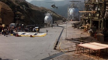 Movie still from “Hooper” (1978), directed by Hal Needham – A helicopter flying over an industrial area with people; Extreme Wide shot, High angle