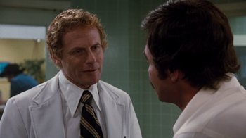 Movie still from “Hooper” (1978), directed by Hal Needham – A man in a white lab coat and a man in a black and yellow striped neck tie; Close Up shot, Over the shoulder angle