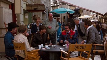 Movie still from “Hooper” (1978), directed by Hal Needham – A group of people sitting at a table outside; Wide shot, Over the shoulder angle