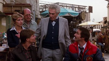 Movie still from “Hooper” (1978), directed by Hal Needham – A group of people standing around a man in a suit; Medium shot, Over the shoulder angle