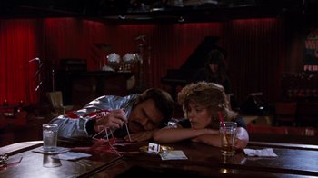 Movie still from “Hooper” (1978), directed by Hal Needham – A man and a woman sitting at a table in front of drinks; Wide shot, High angle