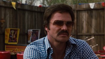 Movie still from “Hooper” (1978), directed by Hal Needham – A person wearing sunglasses and a plaid shirt; Close Up shot, Over the shoulder angle