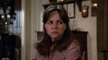 Movie still from “Hooper” (1978), directed by Hal Needham – A woman sitting in front of a fireplace; Close Up shot, Over the shoulder angle