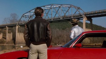 Movie still from “Hooper” (1978), directed by Hal Needham – Two men are standing on the hood of a red sports car; Wide shot, Over the shoulder angle