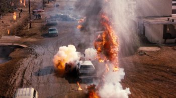 Movie still from “Hooper” (1978), directed by Hal Needham – A car on fire in the middle of a street; Wide shot, High angle
