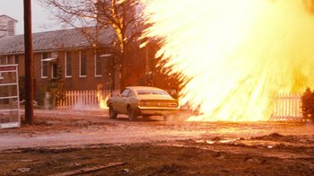 Movie still from “Hooper” (1978), directed by Hal Needham – A car is on fire in the middle of the street; Wide shot, Low angle