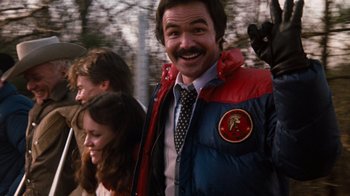 Movie still from “Hooper” (1978), directed by Hal Needham – A man in a red and blue jacket smiling for the camera; Close Up shot, Over the shoulder angle