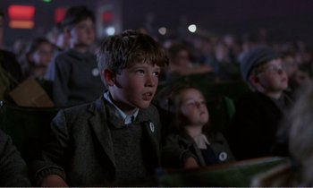Movie still from “Hope and Glory” (1987), directed by John Boorman – A boy and a girl are sitting in the audience; Medium shot, Low angle